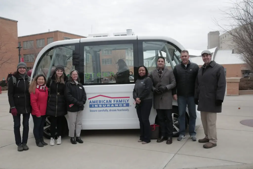 People standing in front of driverless shuttle