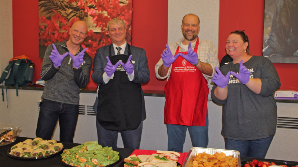 Faculty and staff members serving food at social event.