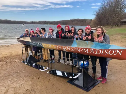 Students standing behind cement canoe they created