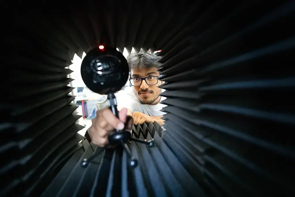 Student adjusting round microphone inside sound insulated box