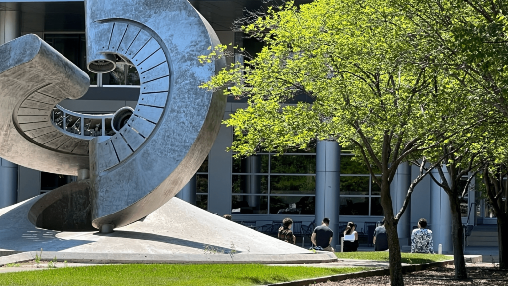 Students sitting outside of Engineering Hall by large fountain/statue