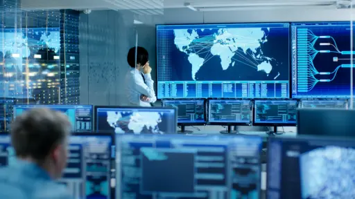 person in a control room looking at digital map of the world with lines connecting multiple locations