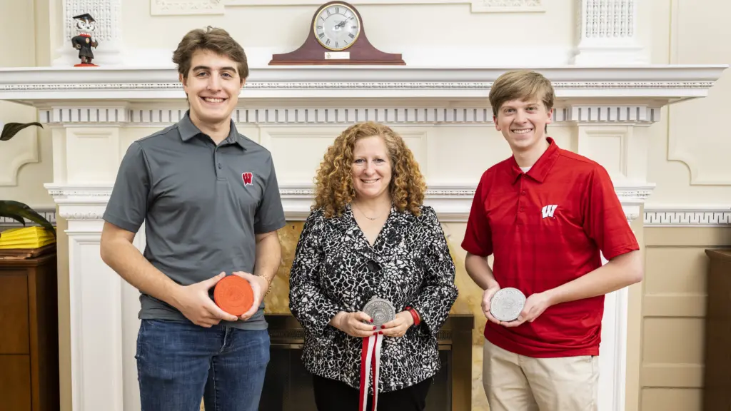 students Teekay Kowalewski (left) and Dylan Zinkgraf (right) present Chancellor Jennifer L. Mnookin with the medallion