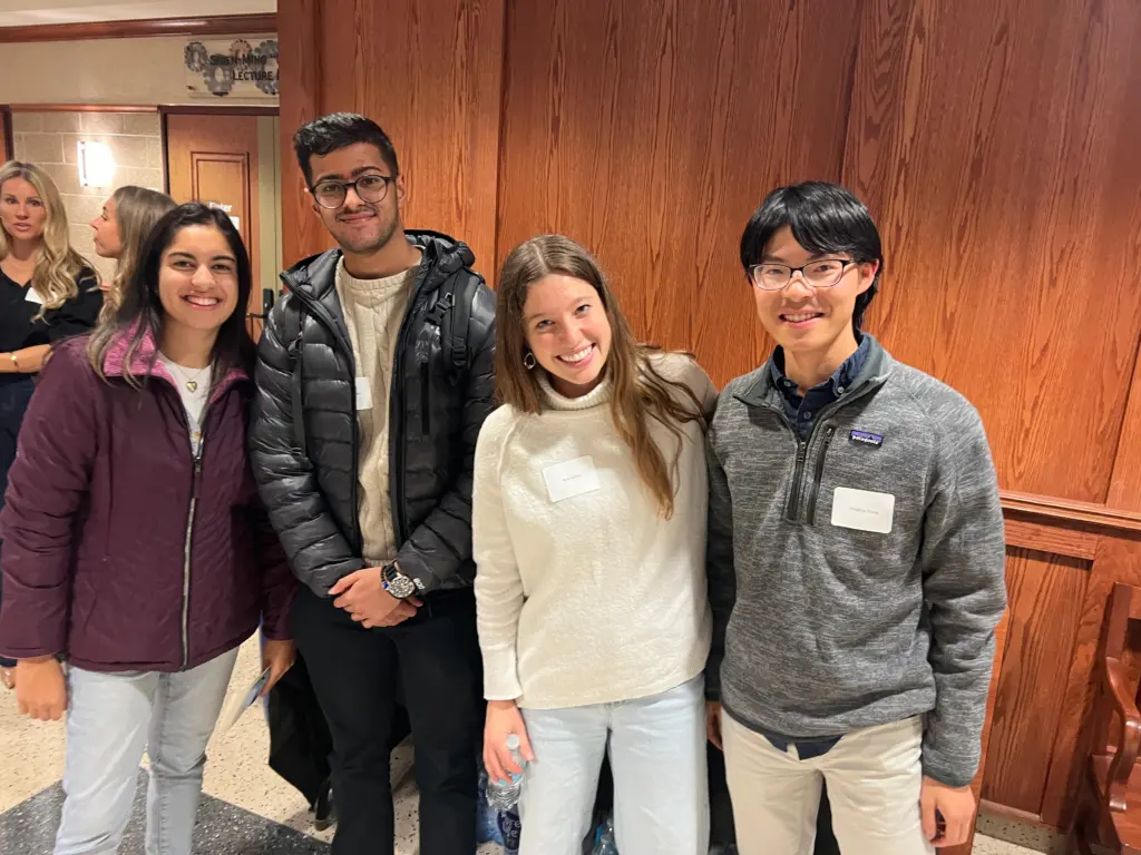 Four students face the camera smiling, dressed casually. 2 females and 2 males.