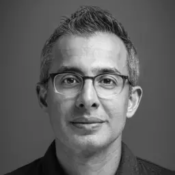 black and white professional headshot, very close-up, man wearing glasses