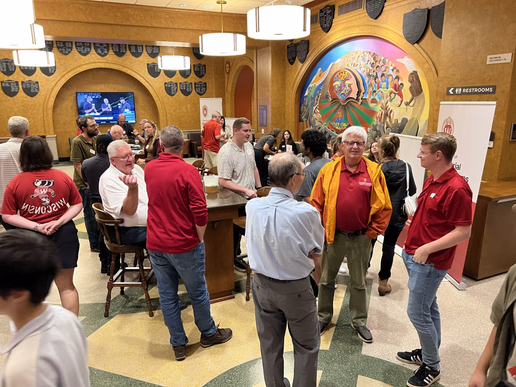 Several people at an indoor social gathering. Some are standing, some are sitting. They are in various phases of individual conversation