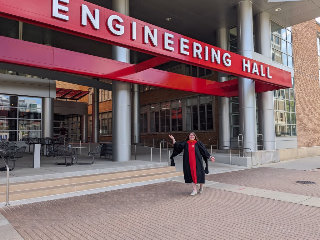 Aryka Thomson standing in front of Engineering Hall in graduation gown.