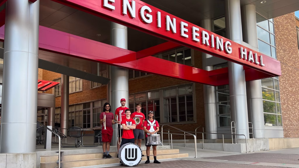 Five UW-Madison marching band members in front of Engineering Hall