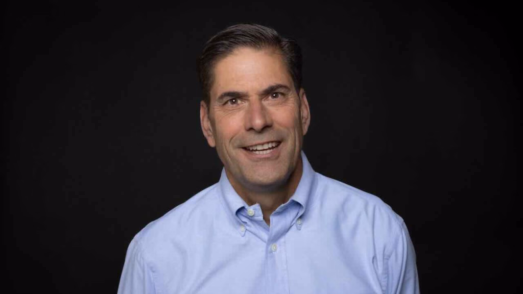 mid-career white man wearing a light blue button-up shirt.