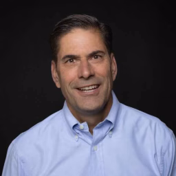 mid-career white man wearing a light blue button-up shirt.