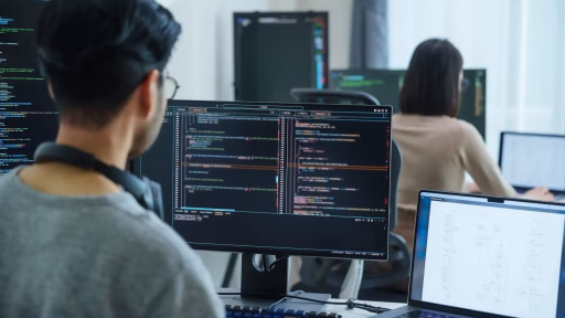 Individual looking at two computers using AI