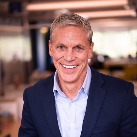 Late career man with light hair wearing a light blue collared shirt under a dark blazer