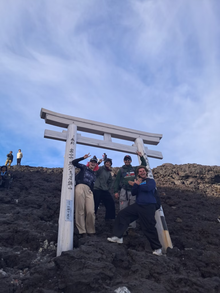 Lucy smiles and poses with friends at the top of Mount Fuji