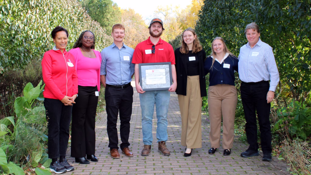 Transit Facility team members pose with an NCEES award plaque outside on a sunny day.