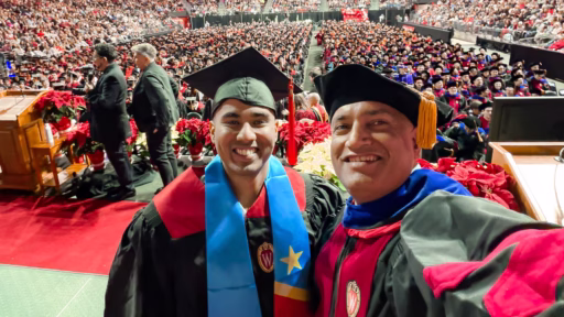 Dean Ranjan on stage with a graduating student at the 2025 Winter Commencement ceremony with a view of the crowd behind them