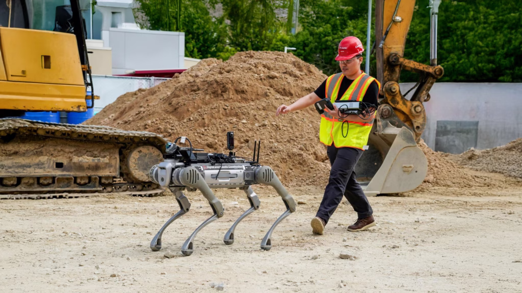 A student follows a robotic dog on a construction site