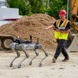 A student follows a robotic dog on a construction site