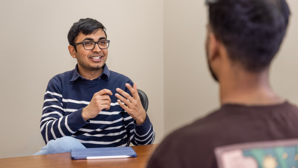 Harsh Sharma discusses a digital twin research project with a student in his office