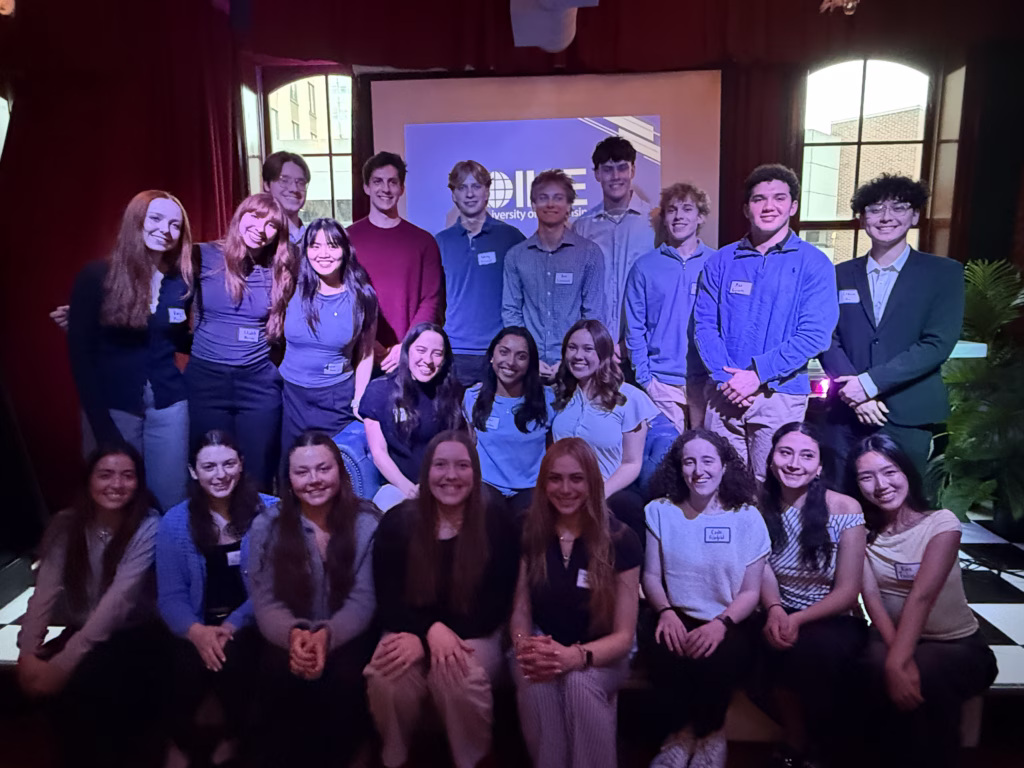 A large group of college students posing together on a low indoor stage